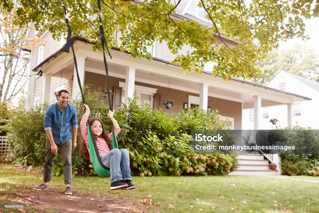 Father Pushing Daughter On Garden Swing At Home